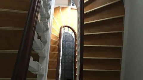 Spiralformet trapp sett ovenfra, med hvitt rekkverk og gulnede tretrinn.