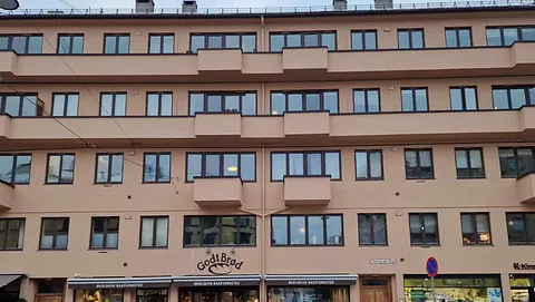 Moderne bygård med lyse fasader, rette linjer og balkonger, butikker i første etasje.