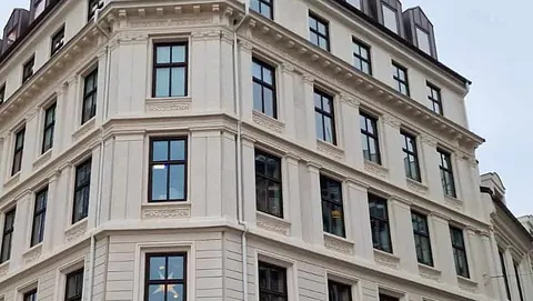 Elegant hjørnebygning i klassisk stil med ornamenterte fasadedetaljer og mørke vinduskarmer.